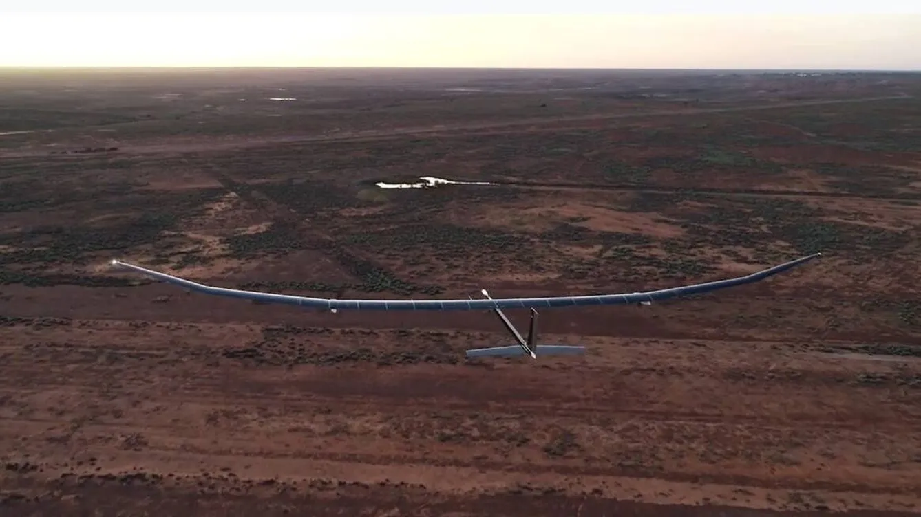 Aerial view of a high-altitude drone flying over a remote, arid landscape at sunset.