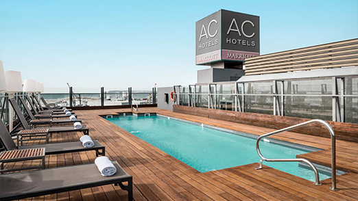 AC Hotels rooftop pool with lounge chairs and city view.