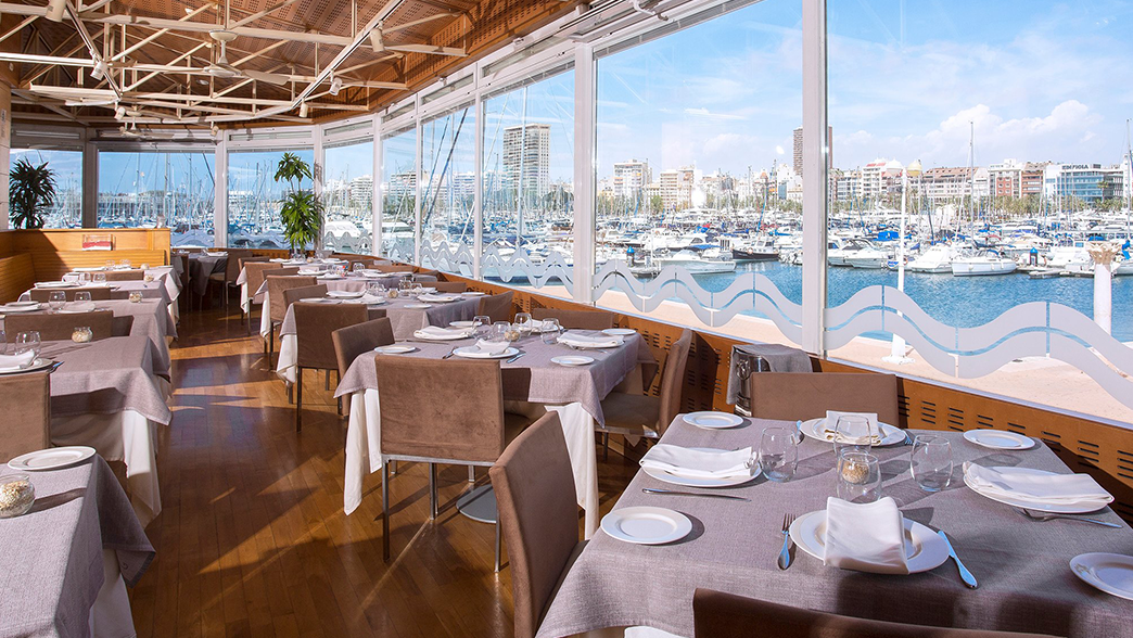 Elegant restaurant with marina view and neatly set tables.