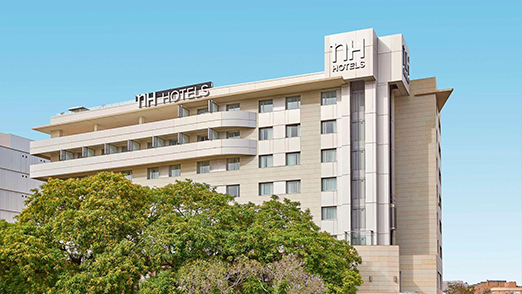 NH Hotels building surrounded by greenery.