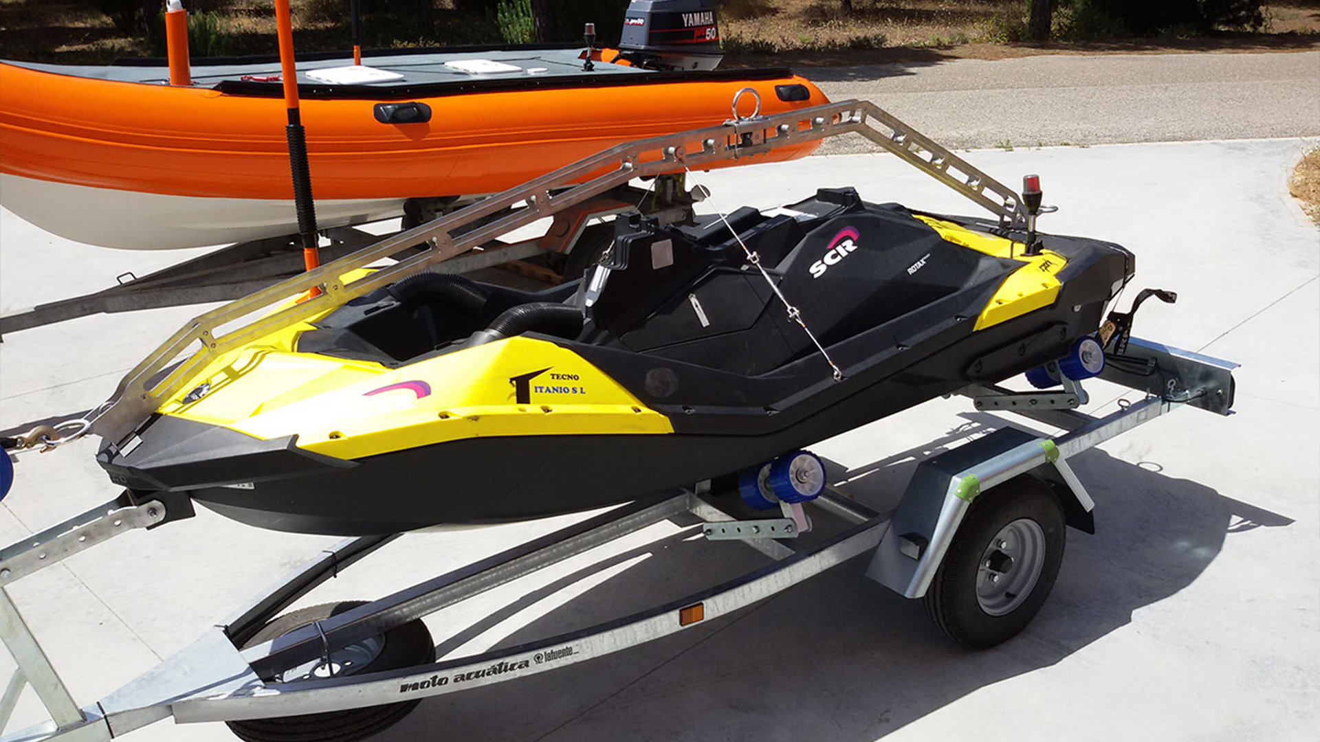 Yellow unmanned surface vehicle (USV) on a trailer, designed for target applications, with an orange boat in the background.